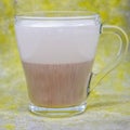 A cup of cappuccino. a transparent cappuccino mug on a yellow-gray background is out of focus.
