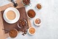 A cup of cappuccino and various types of coffee on a gray table.