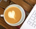 Cup of cappuccino and white laptop on wooden cafe table background Royalty Free Stock Photo
