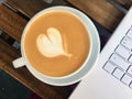 Cup of cappuccino and white laptop on wooden cafe table Royalty Free Stock Photo