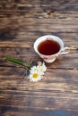 Cup of chamomile tea and chamomile flowers on wooden background. Close-up