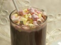 Cup with cocoa, straw and colored marshmallows on a beige tablecloth background