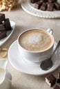 Cup of coffe with milk or cappuccino and chocolate candies, morning coffe