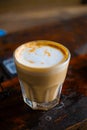 Cup of coffe with milk on a dark background. Hot latte or Cappuccino prepared with milk on a wooden table