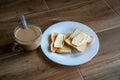 Cup of coffe with milk and two slices of toasted sandwich buttered bread on a white plate. Healthy breakfast with coffee. Side