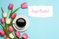 Cup of coffe and pink tulips on blue background. Words Happy Monday. Spring coffee concept. top view, flat lay Royalty Free Stock Photo