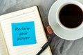 Cup of coffee and adhesive note on notepad with text reclaim your power