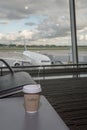 Cup of coffee in airport`s business lounge with aircraft Royalty Free Stock Photo