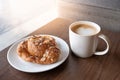 A cup of coffee with almond croissant in the morning light