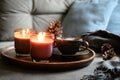 Cup of coffee, aroma candles served in wooden tray in cozy home interior. Simple scandinavian home decor. Close up.