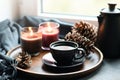 Cup of coffee, aroma candles served in wooden tray in cozy home interior. Simple scandinavian home decor. Close up.