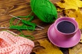 Cup of coffee, ball of yarn, knitting, knitted scarf and yellow maple leaves on wooden table. Autumn still life Royalty Free Stock Photo