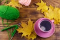 Cup of coffee, ball of yarn, knitting, knitted scarf and yellow maple leaves on wooden table. Autumn still life Royalty Free Stock Photo