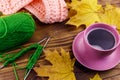 Cup of coffee, ball of yarn, knitting, knitted scarf and yellow maple leaves on wooden table. Autumn still life Royalty Free Stock Photo