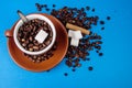 Cup of coffee with beans from above on blue background with cinnamon and sugar Royalty Free Stock Photo