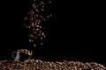 A cup with coffee beans in the air flying in flight like a spray. On a black background, coffee shop advertising concept, copy