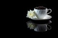 Cup with coffee beans anf white chrysanthemum on a black reflecti