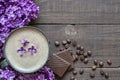 Cup of coffee with coffee beans, chocolate and lilac flowers over rustic wooden background Royalty Free Stock Photo