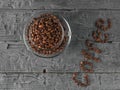 A Cup of coffee beans and coffee inscription lined with coffee beans on a black wooden table. Grains for the preparation of the