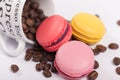 Cup with coffee beans with colorful delicious French macaroons on white background close up Royalty Free Stock Photo