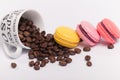 Cup with coffee beans with colorful delicious French macaroons on white background close up Royalty Free Stock Photo