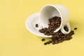 Cup with coffee beans falling on yellow background Royalty Free Stock Photo