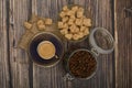 A Cup of coffee, coffee beans in a glass jar and pieces of brown sugar on a wooden background Royalty Free Stock Photo