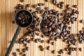 A cup of coffee beans and a measuring spoon on bamboo mat Royalty Free Stock Photo