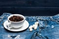 Cup with coffee beans, refined sugar lay on jeans near zip, denim background. Fresh brewed coffee concept. Mug full of Royalty Free Stock Photo