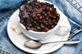 Cup with coffee beans, refined sugar and spoon on plate, denim background. Freshly roasted coffee concept. Mug full of Royalty Free Stock Photo