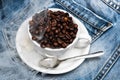 Cup with coffee beans, refined sugar and spoon on plate, denim background. Mug full of coffee beans on jeans and cloud Royalty Free Stock Photo