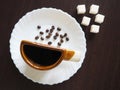 A Cup of coffee and coffee beans on a white plate with sugar cubes next to it Royalty Free Stock Photo