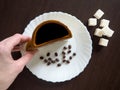 A Cup of coffee and coffee beans on a white plate with sugar cubes next to it Royalty Free Stock Photo