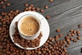 A cup of coffee and coffee beans on a wooden background. Top view. Free space for text.