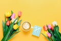 Cup of coffee and beautiful tulips on yellow background, top view Royalty Free Stock Photo