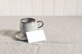 Cup of coffee and blank business, place card. Moody breakfast table stationery mockup scene. Beige linen tablecloth