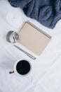 Cup coffee , blue knitted sweater, notebook with pen, clock, candle on bed, top view