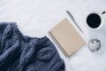 Cup coffee , blue knitted sweater, notebook with pen, clock, candle on bed, top view