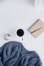 Cup coffee , blue knitted sweater, notebook with pen, clock, candle on bed, top view