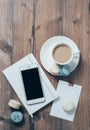 Cup of coffee, blue macaroons and smartphone on wooden table bac