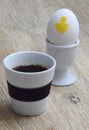 Cup of coffee and a boiled egg with yellow Easter chicken painted on it Royalty Free Stock Photo