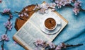 Cup of coffee on a book with cherry blossom branches