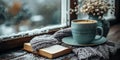 A cup of coffee, a book and a vase of flowers on a window sill. It\'s snowing outside