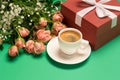 Cup of coffee, bouquet of roses and red gift box on green background, copy space, close up, womens day concept Royalty Free Stock Photo