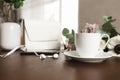 Cup of coffee, bouquet of anemone, purple roses, woman handbag, phone on table