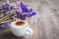 A cup of coffee with bouquet of violet dried flowers on wooden f