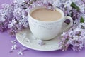 Cup of coffee and branches of blooming lilac