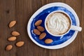 Cup of coffee with cappuccino, almonds on a brown wooden table Royalty Free Stock Photo