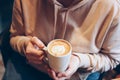 Cup of coffee cappuccino with foam heart in female hands at cafe, close up Royalty Free Stock Photo