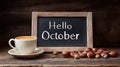Cup of coffee and chalkboard with text Hello October surrounded by hazelnuts on rustic wooden table Royalty Free Stock Photo
